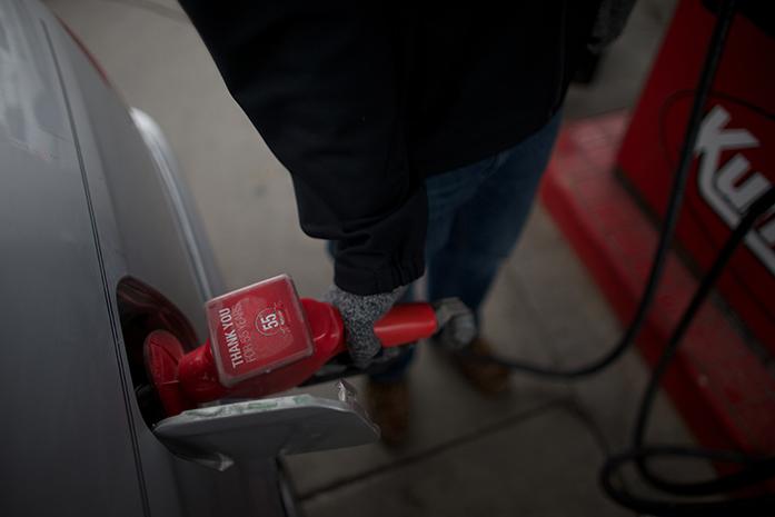UI student Mason Beezley fills up a car with gas on Tuesday, Dec. 16 at the Kum and Go on East Burlington in Iowa City. The price of gas is currently $2.43.