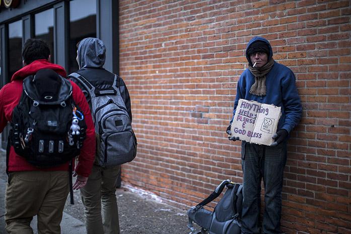 A+homeless+man+holds+up+a+sign+as+two+students+pass+by+Tuesday%2C+Jan.+21%2C+2015.+Work+for+a+new+homeless+shelter+has+been+underway+to+help+keep+the+homeless+safe+from+the+harsh+weather.+%28The+Daily+Iowan%2FSergio+Flores%29