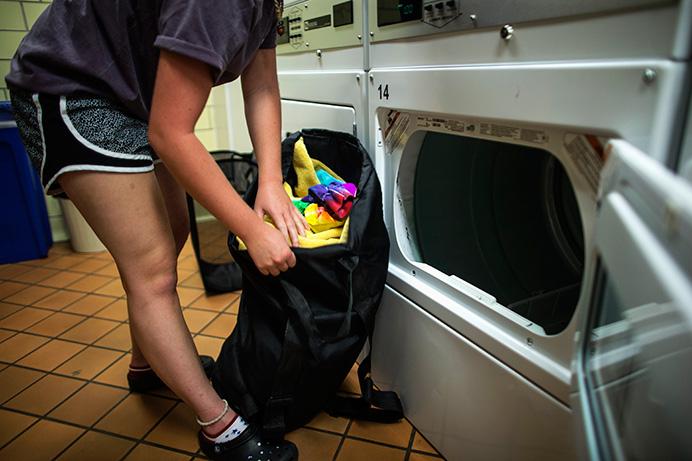 UI freshmen Delaney Soule, who lives on campus, pulls her laundry out of a dryer in Burge on Wednesday. Some students who live off campus have begun using residence-hall facilities to do laundry in an effort to save money. (The Daily Iowan/Sergio Flores)