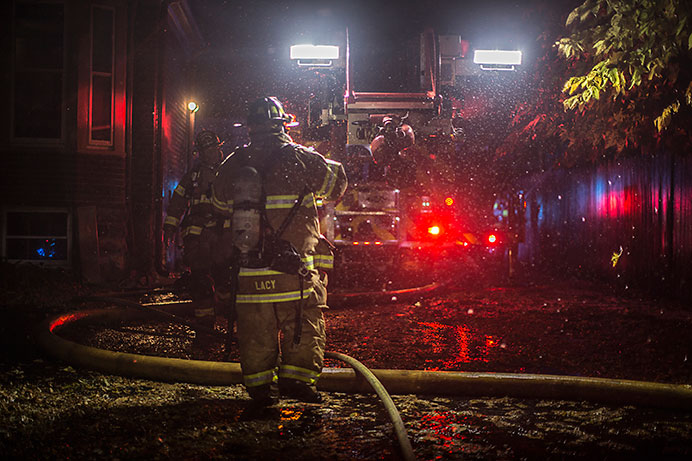 Firefighters work on the scene of a house fire on College Street on Tuesday. Officials believe that the house fire was started by a lightning strike. (The Daily Iowan/Sergio Flores)