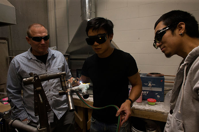 Steve Mcguire (left) and Waiting Cheng (right) watch Willy Tan (middle) welding the parts at the Studio Arts Building on Friday, Oct. 30, 2015. (The Daily Iowan/Peter Kim)