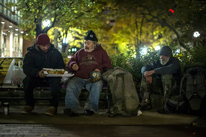 (Right to Left) “Warpath”, “Mike” and “Ron” sit in the Ped Mall on Sunday. They had just been given pizza by a pizza delivery driver. There is an effort in Iowa City to try and make more shelters available for homeless individuals. (The Daily Iowan/Sergio Flores)