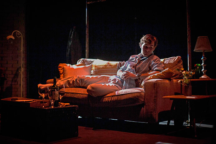 Actor Mathias Blake laying on the stages couch during a scene transition at a rehersal for the play Known, on Nov 3, 2015. Known follows the characters Mimi Ford, Reena and Dylan in a small New York City apartment. (Daily Iowan/Jordan Gale) 