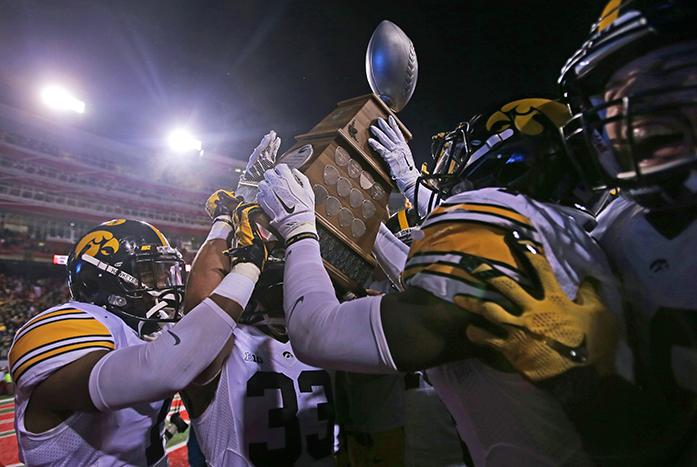 The Iowa team picks up the Hy-Vee Heroes Trophy after the Iowa-Nebraska game at Memorial Stadium on Friday, Nov. 27, 2015. The Hawkeyes defeated the Cornhuskers, 28-20, to finish off a  perfect regular season. (The Daily Iowan/Margaret Kispert)