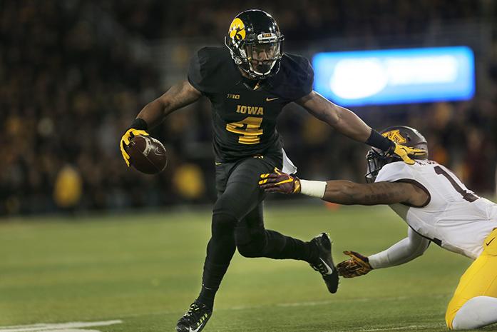 Iowa wide receiver Tevaun Smith tries to avoid a tackle by Minnesota defensive back Antonio Johnson during the Iowa-Minnesota game at Kinnick on Saturday, Nov. 14, 2013. The Hawkeyes defeated the Golden Gophers, 40-35 to stay perfect on the season. (The Daily Iowan/Margaret Kispert)