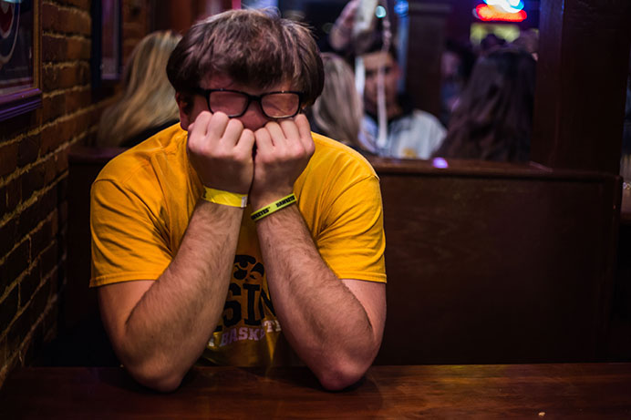 A fan is overcome with sadness in the Sports Column when the score became final in the Big Ten title games against Michigan State. People crowded the bars downtown to watch Iowa play on Saturday, Dec. 5, 2015. (The Daily Iowan/Anthony Vazquez)