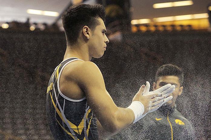 Iowa gymnast Cyrus Dober-Mofid chalks his hands before hitting the parallel bars in Carver-Hawkeye on Feb. 1 2015. Dober-Mofid has been one of the most consistent gymnasts this season. (The Daily Iowan/Margaret Kispert)
