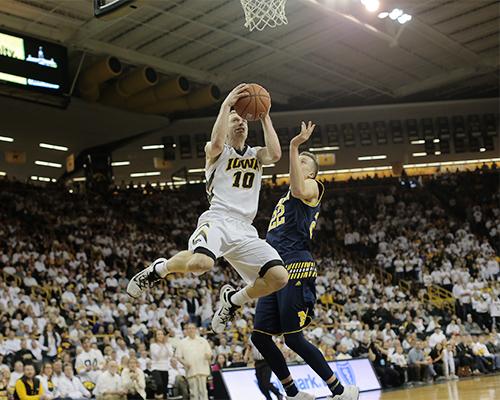 Iowa guard Mike Gesell goes up for a layup against Michigan forward Duncan Robinson during the Iowa-Michigan game in Carver-Hawkeye on Sunday, Jan. 17, 2015. The Hawkeyes defeated the Wolverines, 82-71. (The Daily Iowan/Margaret Kispert)