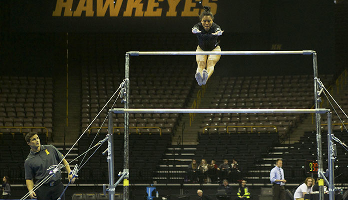 Senior Johanny Sotillo looks to get control of the bars after performing a move in the air Monday January 18th, 2016. The womens gymnastics faced off against the University of Denver at Carver Hawkeye Arena. (The Daily Iowan/Kyle Close)