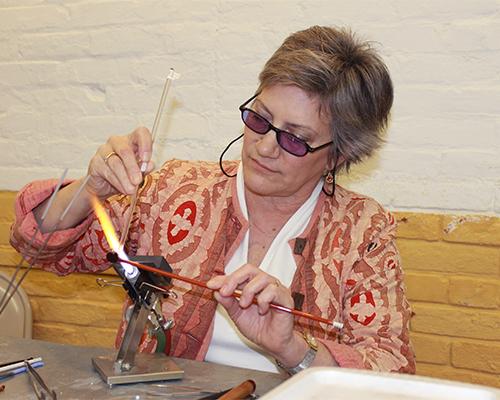 Instructor Wendy Ford uses flame to create glass-implosion beads at Beadology Iowa on Thursday. Ford teaches numerous classes at Beadology Iowa throughout the year. (The Daily Iowan/McCall Radavich)