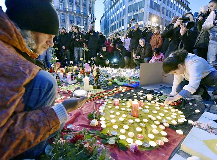 People bring flowers and candles to mourn for the victims at Place de la Bourse in the center of Brussels, Tuesday, March 22, 2016. Bombs exploded at the Brussels airport and one of the city's metro stations Tuesday, killing and wounding scores of people, as a European capital was again locked down amid heightened security threats. (AP Photo/Martin Meissner)