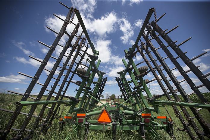 Farming machinery stands tall next to crop fields on the Meade Family Farm in Tiffin on Tuesday, June 28, 2016. In light of a recent EPA investigation, information has emerged linking the use of atrazine, a common herbicide sprayed across Iowa farm land, with negative health and environmental outcomes. 