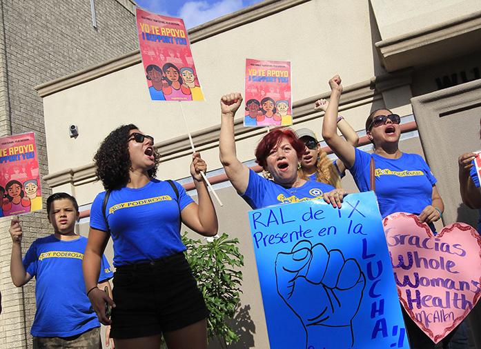 Lucy Ceballos, center, and Isabella Soto, left, members of the National Institute for Reproductive Health, celebrate the U.S. Supreme Court ruling against Texas abortion restrictions in front of Whole Womans Health Monday, June 27, 2016, in McAllen, Texas. Whole Womans Health is a abortion provider that stayed open despite the restrictions as many other providers closed over the past two years.  (Nathan Lambrecht/The Monitor via AP)