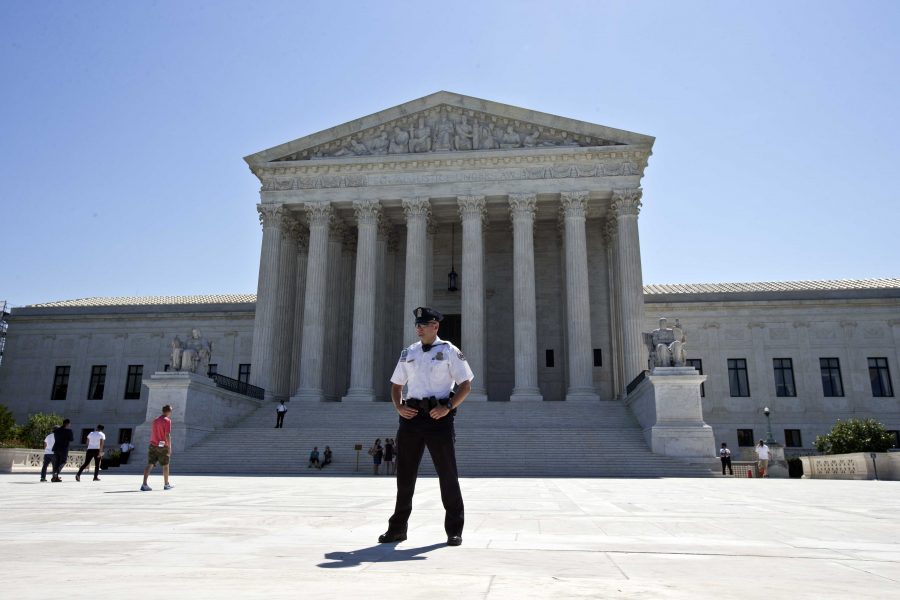 FILE - In this June 20, 2016 file photo, a Supreme Court police officer stands in front of the Supreme Court in Washington as the court announced several decisions.  Justice Antonin Scalia’s sudden death transformed the Supreme Court’s term, shifted power to its liberal wing and started a transition that will be greatly affected by who wins the presidency. It was a term unusual in other ways, too. Justice Clarence Thomas broke a 10-year silence following his good friend’s death to ask questions during an oral argument. Senate Republicans shunned any action on President Barack Obama’s nominee to restore the court to its full nine-member strength. And four cases ended in 4-4 ties. (AP Photo/Alex Brandon, File)