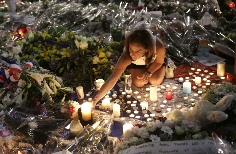 A woman lights candles at a new memorial in a gazebo in a seaside park on the famed Promenade des Anglais in Nice, southern France, Monday, July 18, 2016. Mourners formed a human chain to remove flowers, candles and other mementos placed along the Promenade des Anglais as spontaneous memorials to the victims of the Bastille Day attack in preparation to open the westbound lane.(AP Photo/Claude Paris)