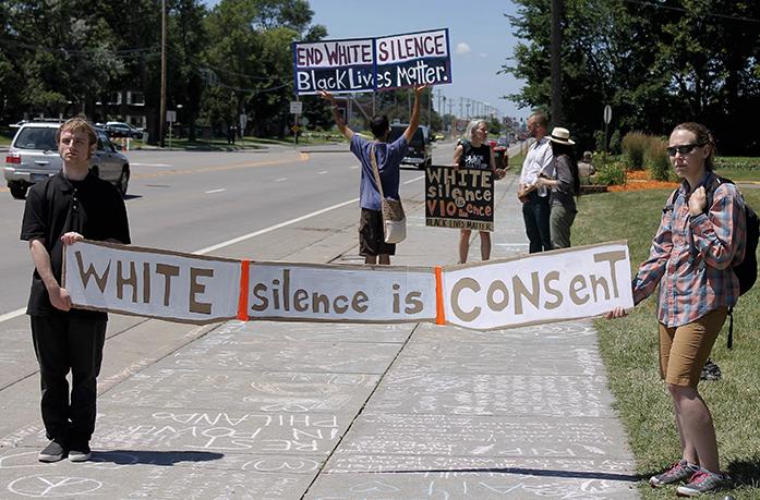 Protesters hold signs on Saturday, July 9, 2016, at the site of two memorials established in memory of Philando Castile in the Minneapolis suburb of Falcon Heights near the spot where Castile was shot and killed by a police officer on July 6. (AP Photo/Skip Foreman)