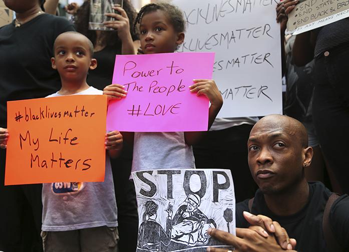 Jashaun Sadler, right, and his twins Malik, left, and Jazlin Sadler listen to speakers during a Black Lives Matter demonstration in New York, Sunday, July 10, 2016. A crowd of about 300 people protested against the shootings of black men by police officers. (AP Photo/Seth Wenig)