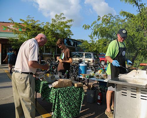 Nathan Moore prepares some hamburger patties and hotdogs for customers outside of the New Pioneer Co-op on Wednesday, Aug. 3, 2016. (The Daily Iowan/Anthony Vazquez)
