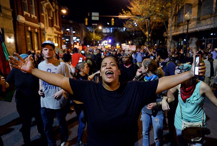 A+protester+gestures+while+marching+down+Church+Street+with+other+demonstrators%2C+to+protest+Tuesdays+fatal+police+shooting+of+Keith+Lamont+Scott%2C+during+a+march+through+the+streets+of+Charlotte%2C+N.C.%2C+Friday%2C+Sept.+23%2C+2016.++After+darkness+fell%2C+dozens+of+people+carried+signs+and+chanted+to+urge+police+to+release+dashboard+and+body+camera+video+that+could+show+more+clearly+what+happened.+%28Jeff+Siner%2FThe+Charlotte+Observer+via+AP%29