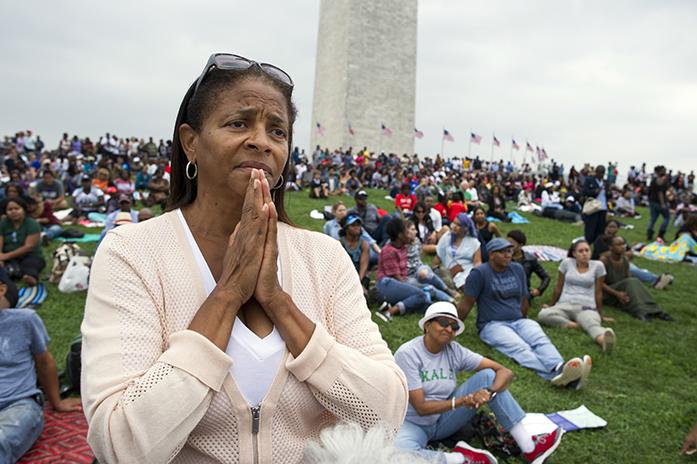 Giselle Shapiro of Los Angeles, holds her hands in prayer on the Washington Monument grounds in Washington, Saturday, Sept. 24, 2016, as she listens to President Barack Obama speak at the dedication and opening ceremony of the Smithsonians National Museum of African American History and Culture in Washington. (AP Photo/Cliff Owen)