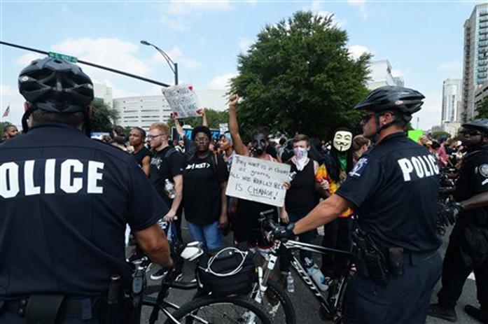 Protesters confront a line of police outside Bank of America Stadium in Charlotte, N.C., Sunday, Sept. 25, 2016. The Carolina Panthers hosted an NFL football game with the Minnesota Vikings at the stadium. When the national anthem was played, the protesters all dropped to one knee as many NFL players have been doing for weeks to call attention to issues, including police shootings. (Diedra Laird/The Charlotte Observer via AP)