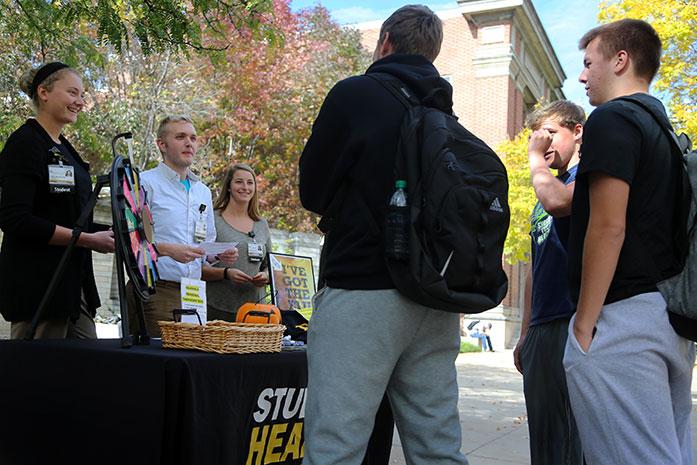 UI senior nursing students Claire Benschoter, Austin Wulf, and Sara Anderson stand on the T. Anne Cleary Walkway on Monday. They informed people about flu shots and student health and wellness. (The Daily Iowan/Alex Kroeze)