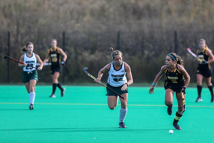 Iowa forward Natalie Cafone runs down the field with Michigan State midfielder Lauren Bonness during the Iowa v. Michigan State field hockey match at Grant Field on Friday, Oct. 21, 2016. The Hawkeyes defeated the Spartans 5-3. (The Daily Iowan/Anthony Vazquez)