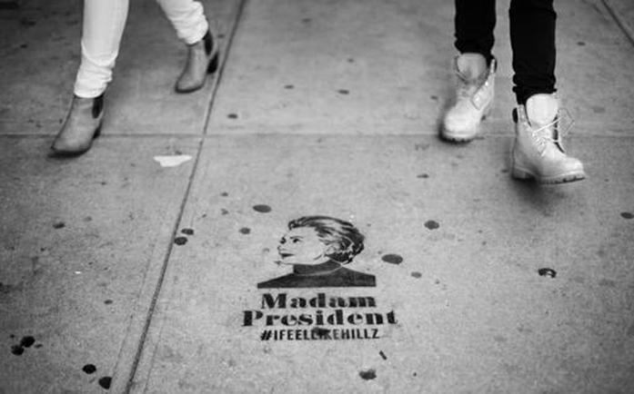 Pedestrians walk past a sidewalk message depicting Democratic presidential candidate Hillary Clinton a few blocks from her planned election night rally in New York, Tuesday, Nov. 8, 2016. (AP Photo/David Goldman)