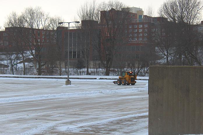 Small bulldozers scrape freshly fallen snow off of the EPB parking lot on February 14, 2016.  The snow started falling early in the morning, making Valentines Day start by giving Iowa City residents the cold shoulder. (The Daily Iowan/Riley Leaders)