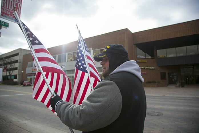 Iraq war veteran Curtiss Ainesworth of Cedar Rapids waves American flags on the pedestrian mall across from the Old Capitol Mall on Sunday, Jan. 29. 2017. Ainesworth hung signs reading, "honk to support our flag" to respond to flag burnings. (The Daily Iowan/Joseph Cress)