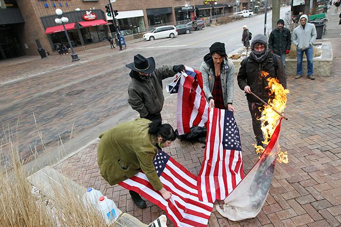 A group of protesters burn American flags on the pedestrian mall along Clinton Street on Thursday, Jan. 26, 2017. (David Scrivner/Iowa City Press-Citizen)