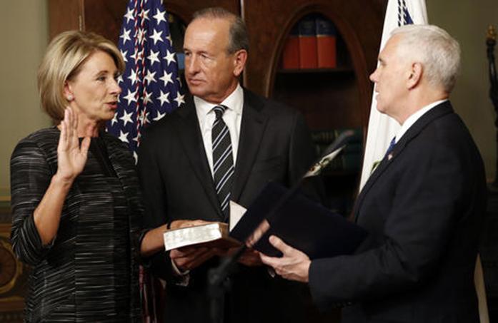 Vice President Mike Pence swears in Education Secretary Betsy DeVos in the Eisenhower Executive Office Building in the White House complex in Washington, Tuesday, Feb. 7, 2016, as DeVos husband Dick DeVos watches. (AP Photo/Pablo Martinez Monsivais)