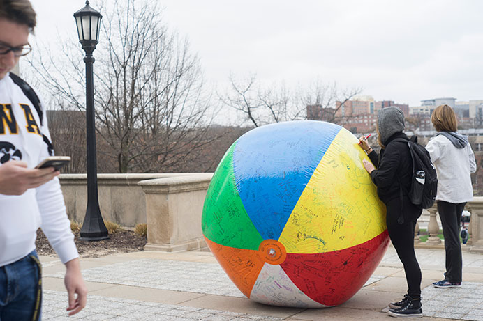 Students write phrases on a beach ball outside the Old Capitol on Tuesday. An event was held in the IMU to discuss the challenges of free speech in America. (The Daily Iowan/Ben Smith)