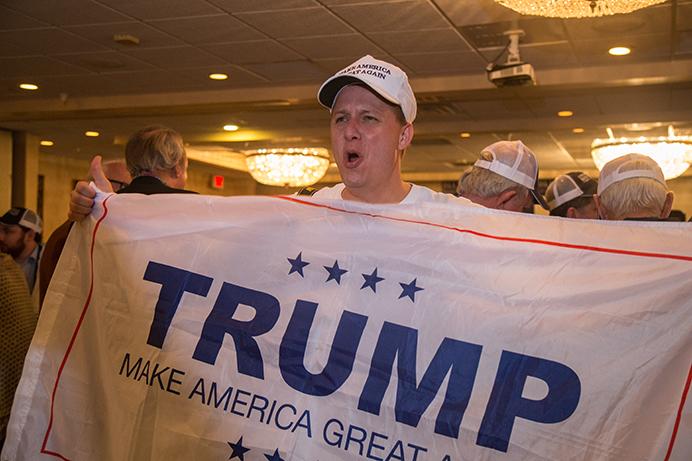 A Donald Trump supporter shows off his Trump flag at the Best Western, in Dubuque, Iowa on Tuesday, Nov. 8, 2016. 1st District Iowa House Representative Republican Rod Blum celebrates his victory with an 8 points lead over Democrat Monica Vernon. (The Daily Iowan/Anthony Vazquez)