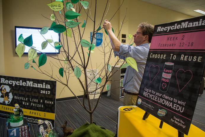 George McCrory of the Sustainability program at Iowa places a leaf on one of the branches. Leaves mark a pledge for an indidivual to do their part improving their recycling habit, in the Sustainability Office in Iowa City, Iowa on Tuesday, Feb. 14, 2017. Recylemania is an national competition which encourages universities to promote and take action in recycling. (The Daily Iowan/Anthony Vazquez)