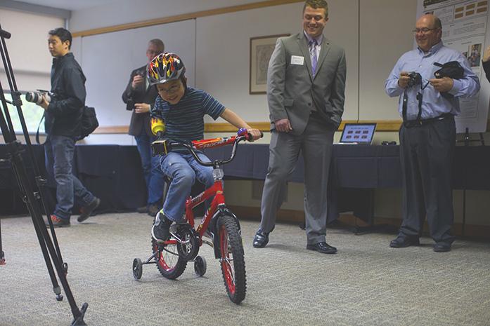 Jonny Cole rides his bike during Senior Design Day for the College of Engineering in the IMU on April 28. UI Visiting Assistant Professor Douglas Cole and 8-year-old Jonny worked with UI engineering seniors Kylie Hershberger, Mitchell Miller, Alicia Truka, and Nathaniel Witt on designing and 3D printing an adaptive device for Jonnys bike. (The Daily Iowan/ Lily Smith)