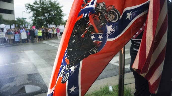 A pro-Trump demonstrator displays her American and Confederate flags within view of the protesters outside the Donald Trump rally in Cedar Rapids, Iowa on Wednesday, June 21, 2017. The arena was filled to capacity and many of the supporters had to be turned away. (James Year/The Daily Iowan)