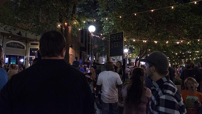 Partygoers walk in the Pedestrian Mall while others buy beer in front of the Field House bar during the Iowa City Downtown District Block Party on Saturday June 25, 2017. The Block Party, hosted by the ICDD was the first use of Iowa City's changed rules allowing open containers for select events downtown (Nick Rohlman/The Daily Iowan)