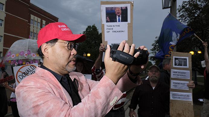 A man wearing a "Make America great again" hat videotapes protestors outside of a Donald Trump rally in Cedar Rapids on Wednesday June 21, 2017. (Nick Rohlman/The Daily Iowan)