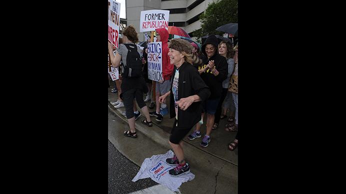 A woman stomps on a Donald Trump t-shirt during a protest outside of a Donald Trump rally in Cedar Rapids on Wednesday June 21, 2017. (Nick Rohlman/The Daily Iowan)