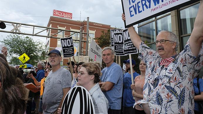 Protesters hold signs  outside of a Donald Trump rally in Cedar Rapids on Wednesday June 21, 2017. (Nick Rohlman/The Daily Iowan)