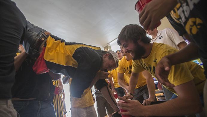 FILE - In this, Saturday, September 3, 2016 file photo, groups of Iowa fans cheer as a man does a keg stand before the first home game of the 2016 football season. Greek leaders at the University of Iowa have issued a ban on events with alcohol in the greek community. (Jordan Gale/The Daily Iowan, file)