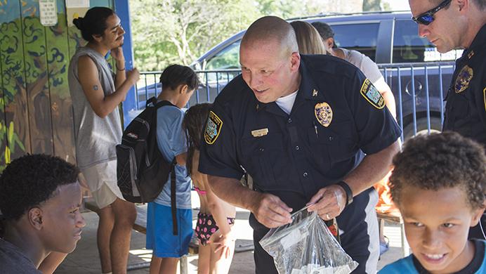 Iowa City Police Chief Jody Matherly hands out temporary tattoos to kids at the National Night Out in Weatherby Park on Tuesday, August 1, 2017. The event gives the community a chance to meet with police officers.  (Gage Miskimen/The Daily Iowan)