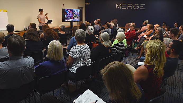 Iowa City community mebers listen to some upcoming public art projects at Merge collective workspace, Wednesday, Aug. 30 2017. The Iowa City Downtown district hosted the event to gather input from the community on possible art projects through the district. (Paxton Corey/The Daily Iowan)