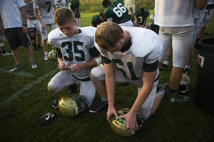 West High players place W stickers on their gold helmets after a West High 4A Mississippi Valley Conference high school football practice at West High on Wednesday, Sept. 13, 2017. The Trojans are 3-0 heading into their cross-town rivalry with 1-2 City High. (Joseph Cress/The Daily Iowan)