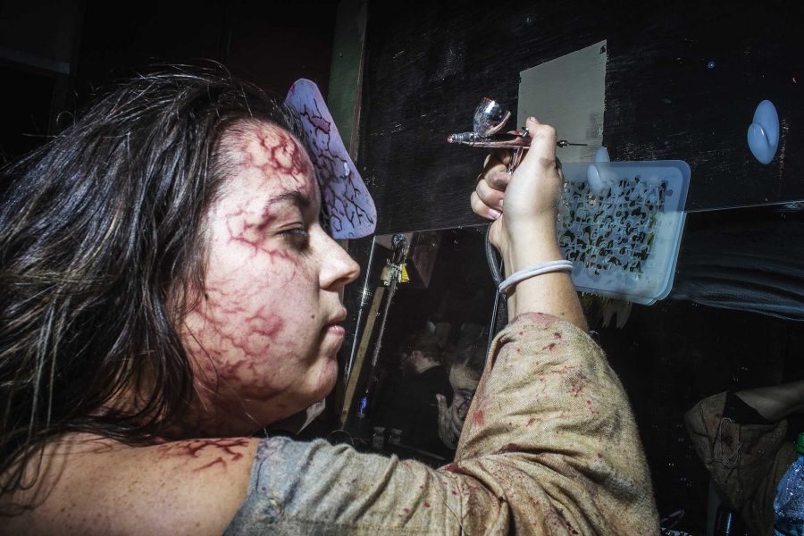 Chelsea Haugh airbrushes fake blood vessels onto her face shortly before the Circle of Ash Scream Park opens for business on Sunday, Oct. 22, in Central City, Iowa. Chelsea has been involved with the organization for the last 11 years and enjoys the variety of skills needed to keep a haunted house running. (James Year/The Daily Iowan)