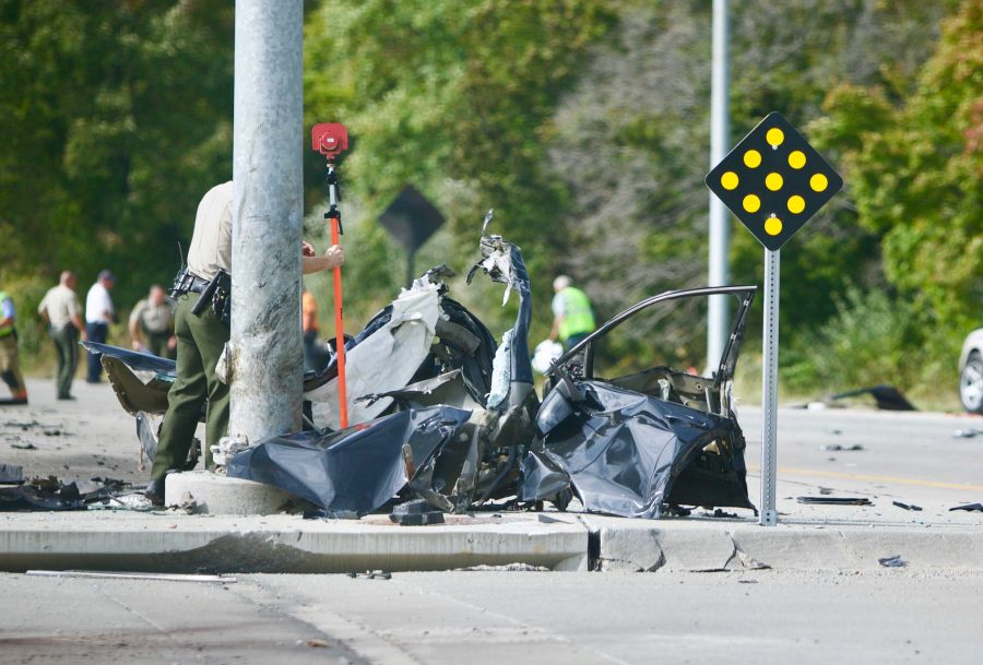 A state patrol officer cleans the scene of a crash on Dubuque and Linder St. on Monday, Oct. 2. (The Daily Iowan/Olivia Sun)