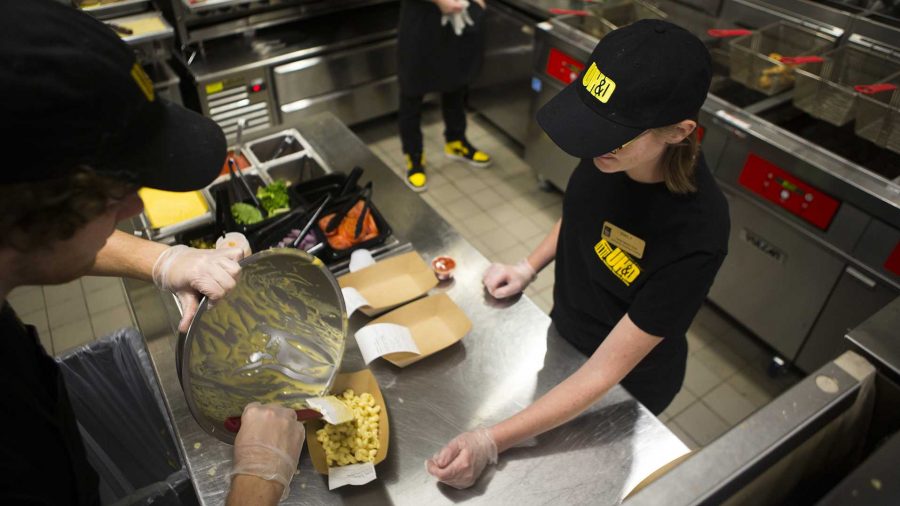 UI sophomore Daniel Lunde helps pour mac n' cheese while UI junior Emily Lowery waits to fulfill the order in the Fire Up Late Night Grill in Catlett Residence Hall on Wednesday, Oct. 25, 2017. The food window opened up Monday to students. They are open Sunday-Thursday, 9 p.m. to midnight. (Joseph Cress/The Daily Iowan)