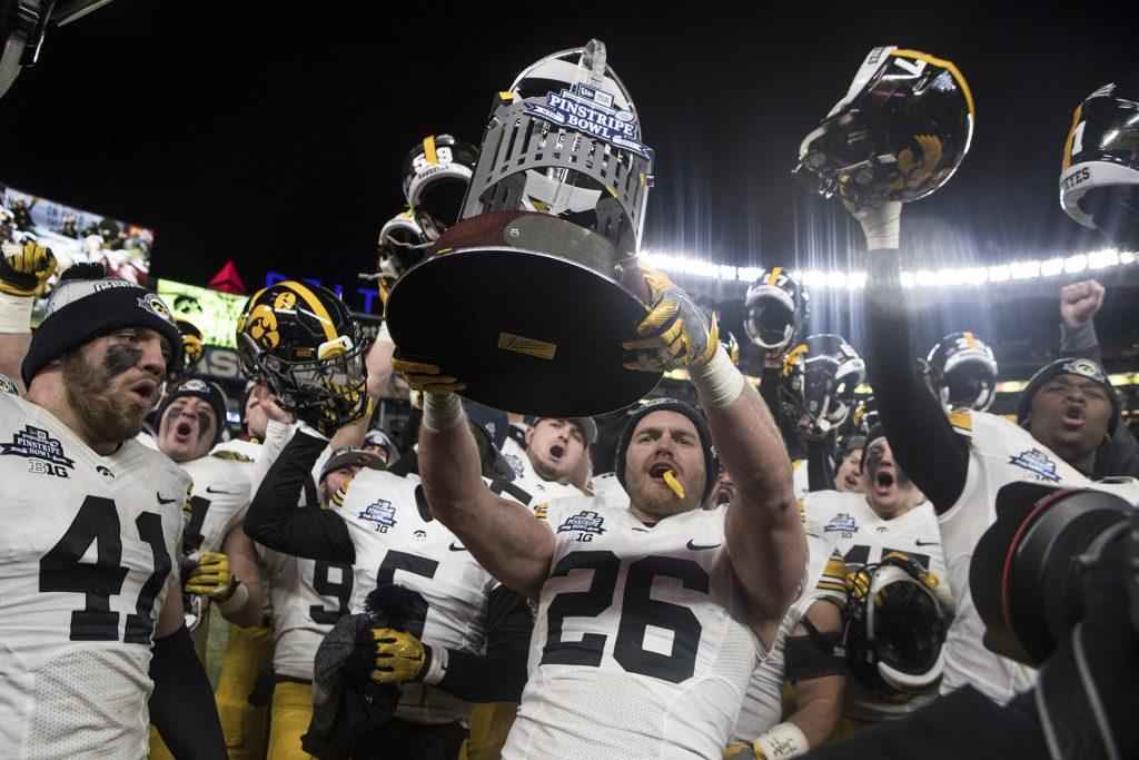 Iowas Kevin Ward (26) holds up the New Era Pinstripe Bowl trophy after the Hawkeyes beat Boston College in the Pinstripe Bowl at Yankee Stadium in New York on Wednesday, Dec. 27. The Hawkeyes went on to win 27-20. (Ben Allan Smith/The Daily Iowan)