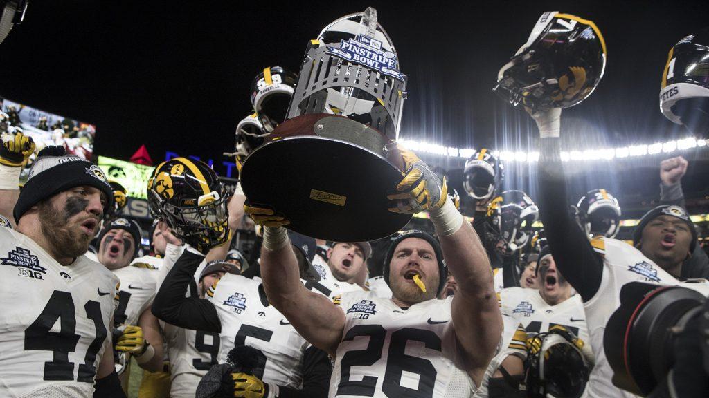 Iowas Kevin Ward (26) holds up the New Era Pinstripe Bowl trophy after the Hawkeyes beat Boston College in the Pinstripe Bowl at Yankee Stadium in New York on Wednesday, Dec. 27. The Hawkeyes went on to win 27-20. (Ben Allan Smith/The Daily Iowan)